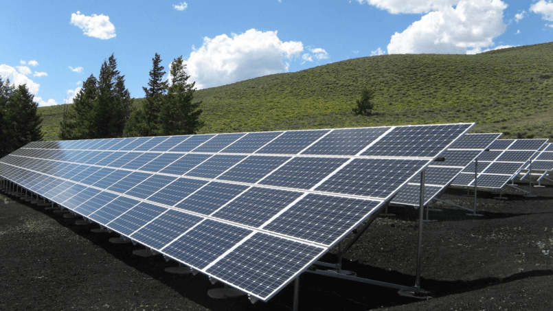 Imagem de painéis na grama para explicar como funciona a energia solar