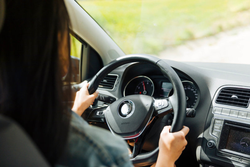 Imagem de uma motorista dirigindo um automóvel com direção hidráulica