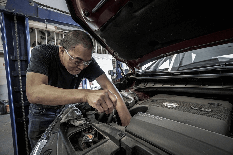 homem fazendo manutenção preventiva no capô de um carro