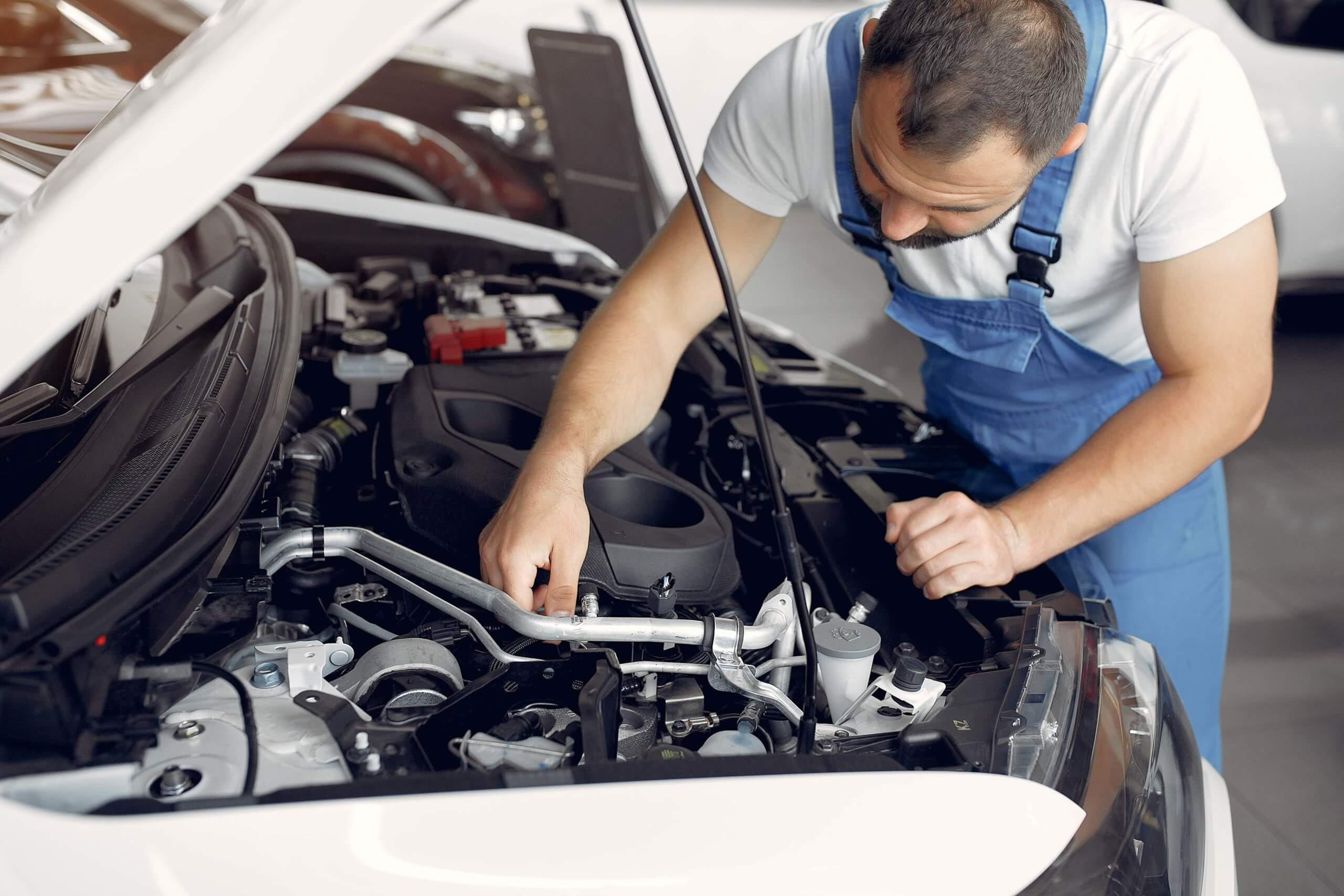 Mecânico de uniforme checando motor de carro