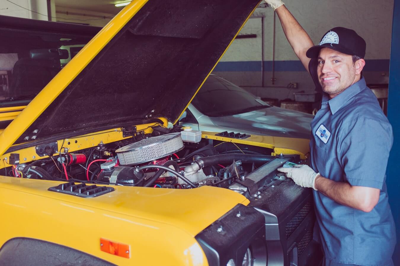 Mecâncio mostrando a parte de dentro de um carro amarelo com capô levantado