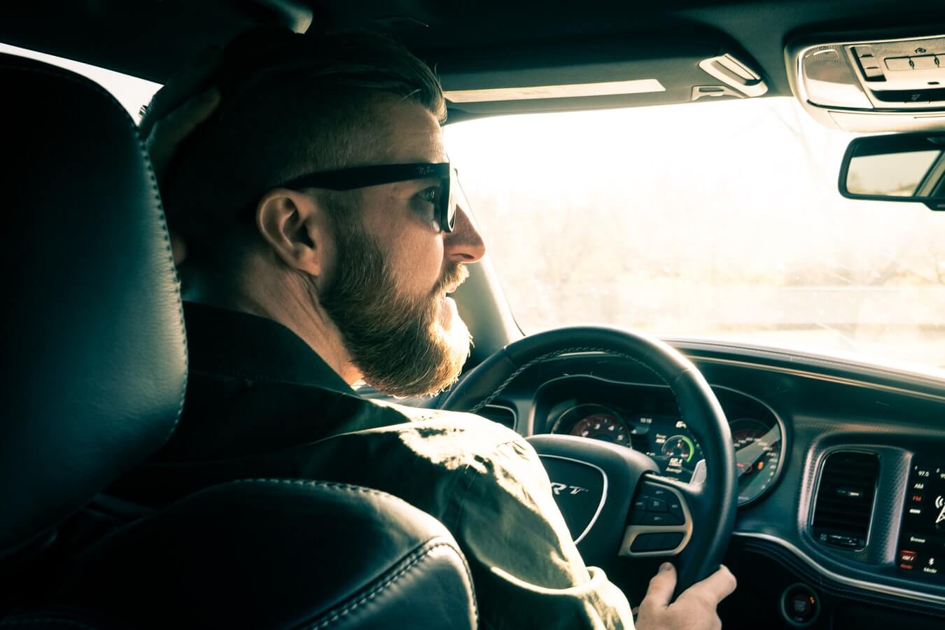 Imagem mostra um homem dentro de um carro, dirigindo