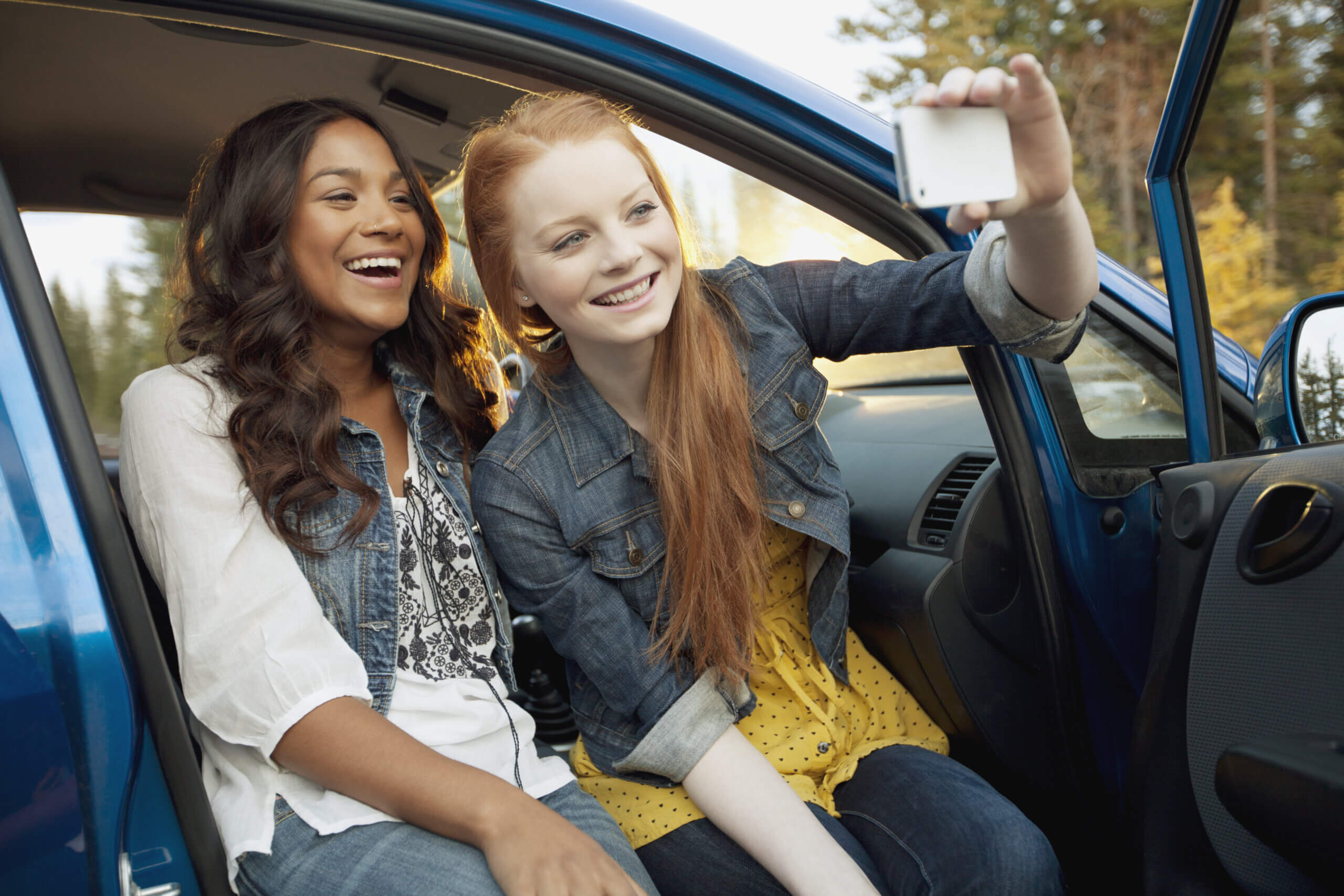 Imagem de um casal de meninas tirando fotos enquanto estão sentadas em um dos tipos de carros para jovens