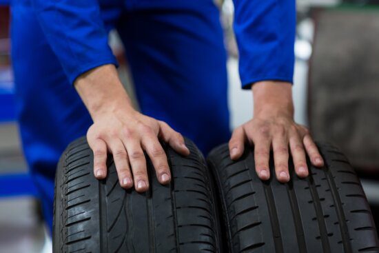 Hands of mechanic touching tyres in repair garage