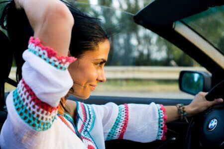 mulher dirigindo carro conversível mexendo no cabelo