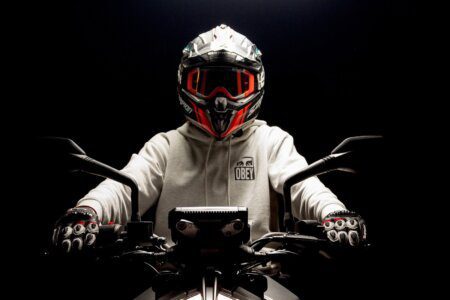 Motociclista de frente em fundo escuro com capacete esportivo