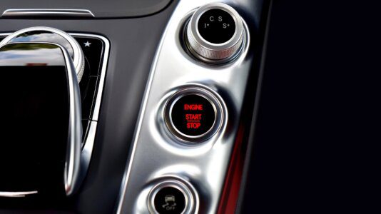 Botões na cor prata e preta com um aviso escrito em vermelho dizendo iniciar ou parar o motor.